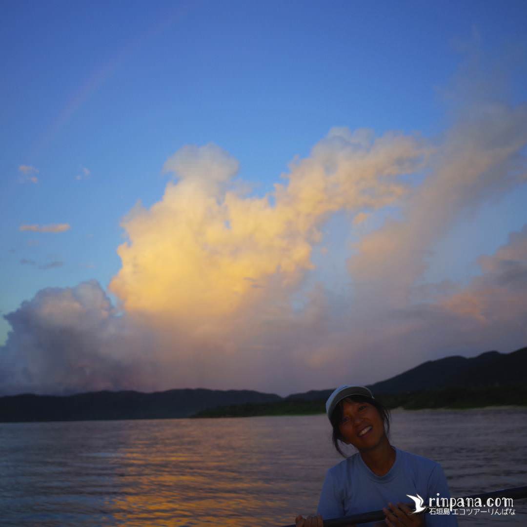 カヌーから夕陽をながめる女性の写真