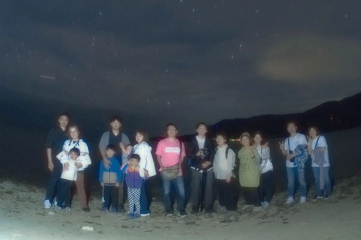 砂浜から眺める広大な星空の下、旅の思い出を形に残す記念写真の撮影シーン